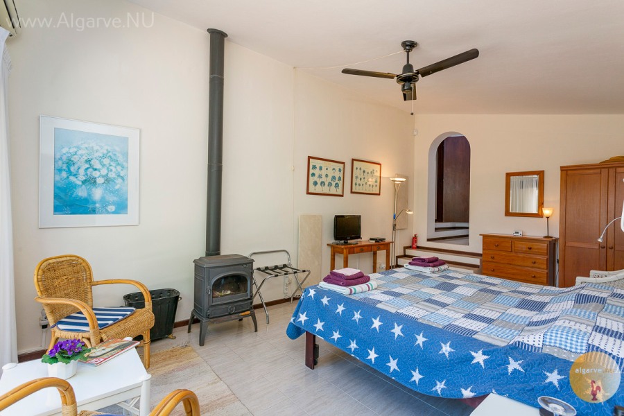 Chambre principale avec salle de bain attenante, panneaux chauffants, air climatisé, mini-réfrigérateur et portes coulissantes donnant sur le jardin.
