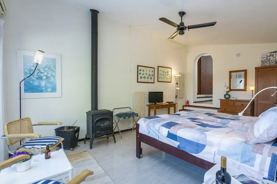 Hoofdslaapkamer met en-suite badkamer, verwarmingspanelen, airconditioning, minikoelkast en schuifpui naar de tuin.